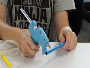 A student gluing their pen before placing it on the Doodle Bot.